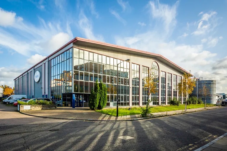 Street level view of a modern industrial building with reflective glass windows in London, England