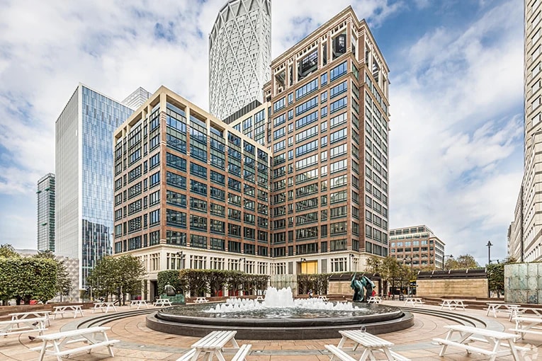 Exterior view of 25 Cabot Square in London E14, showing modern coworking space with fountain plaza and outdoor seating in Canary Wharf.