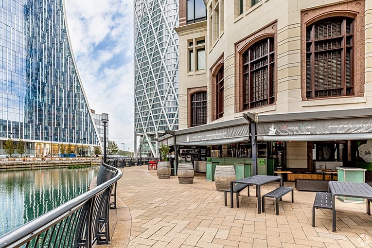 Riverside view outside 25 Cabot Square in London E14, showing Amerigo Vespucci Italian restaurant with outdoor seating along the Canary Wharf dock.
