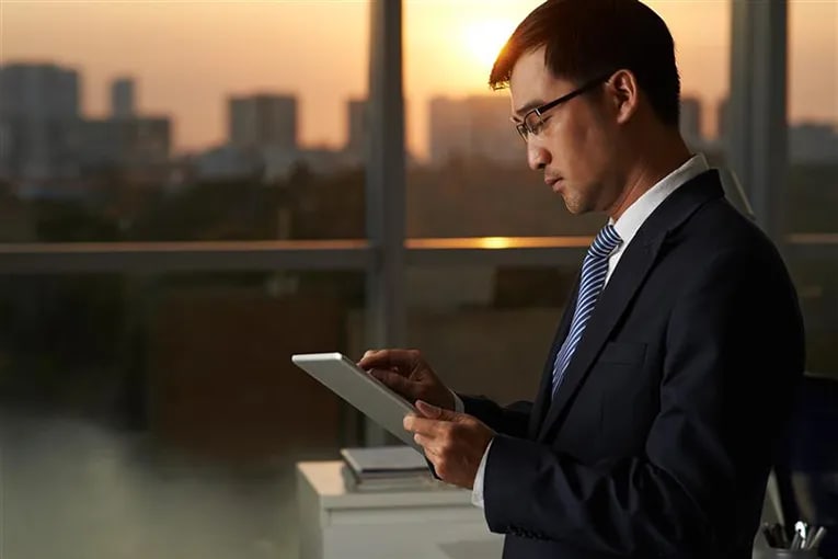 A man in a suite looking at a tablet and registering to bid for commercial auctions