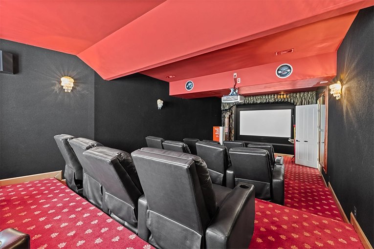 Private movie theater with leather seating, projection screen, and red carpet inside the Atlanta White House mansion.