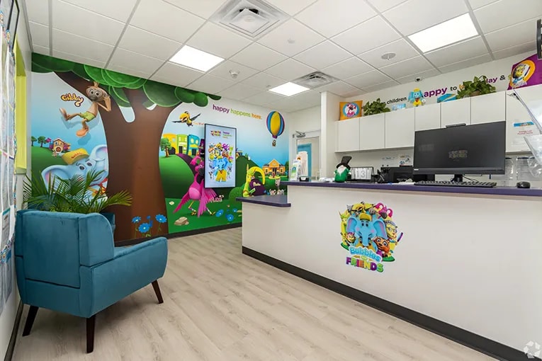 Interior view of The Learning Experience showing the front desk with a chair in the waitingroom and a mural on the wall