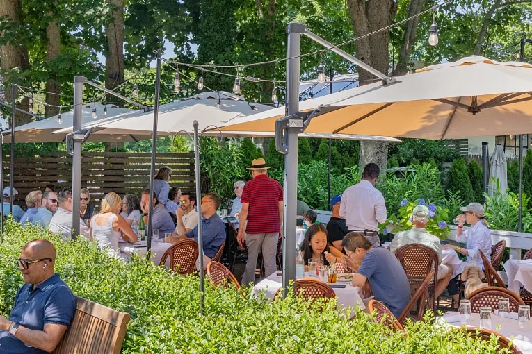 Diners under umbrellas at an outdoor restaurant in Bridgehampton, NY.