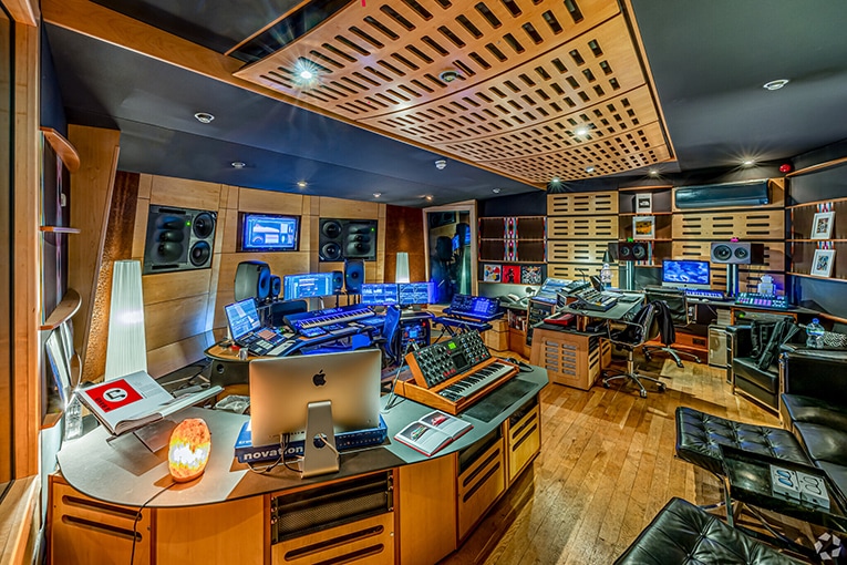Interior of a high-end coworking studio in London designed for music production and digital content creation, featuring professional audio equipment, soundproofing, and multiple editing workstations.