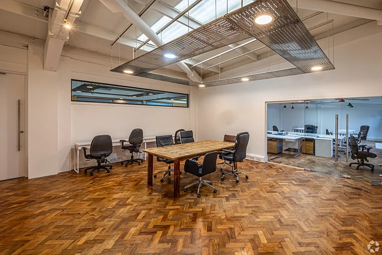 Private coworking office in London with dedicated desks, meeting table, and glass-partitioned workspaces in a modern shared office setting.